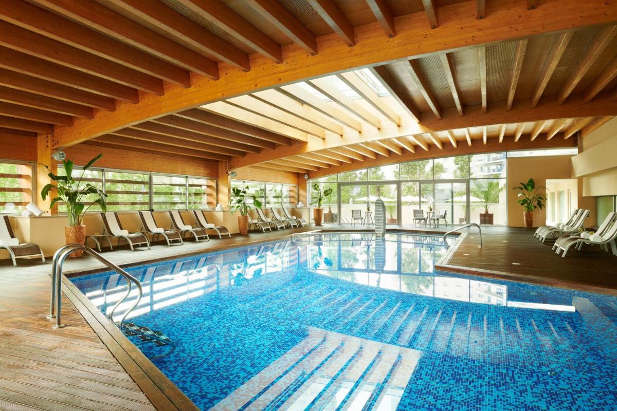 uma grande piscina com cadeiras em um prédio em Corinthia Lisbon em Lisboa
