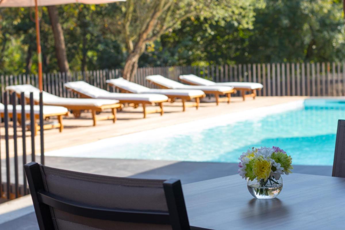 uma mesa com um vaso de flores ao lado de uma piscina em Quinta do Pedregal Hotel & Spa em Vila Nova de Gaia