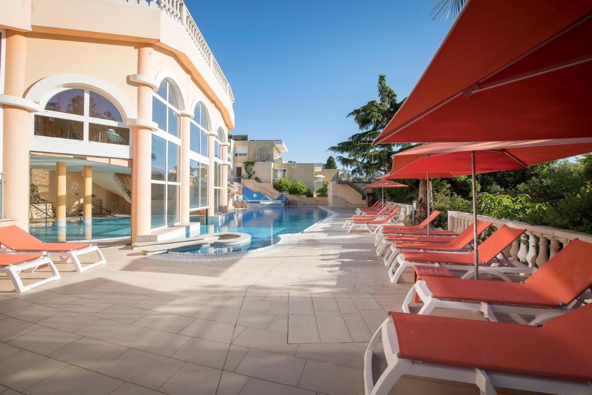 une rangée de chaises et de parasols à côté d'une piscine dans l'établissement Résidence les Tourelles, à Sainte-Maxime