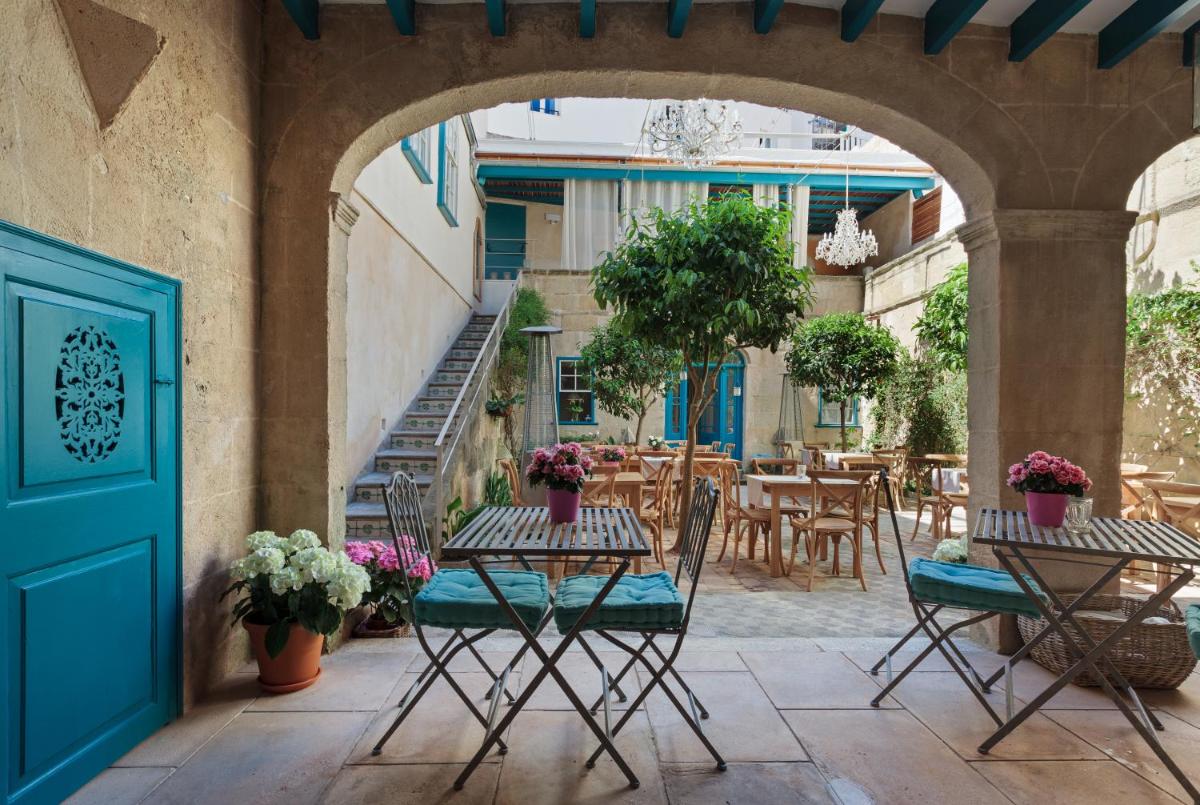 Un patio al aire libre con mesas y sillas y una puerta azul. en Jardí de Ses Bruixes Boutique Hotel, en Mahón