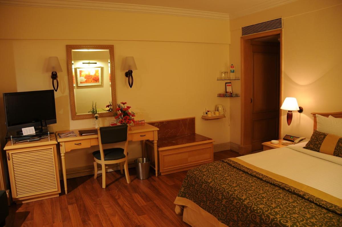 a hotel room with a bed and a desk with a computer at Ramada Plaza By Wyndham Palm Grove in Mumbai