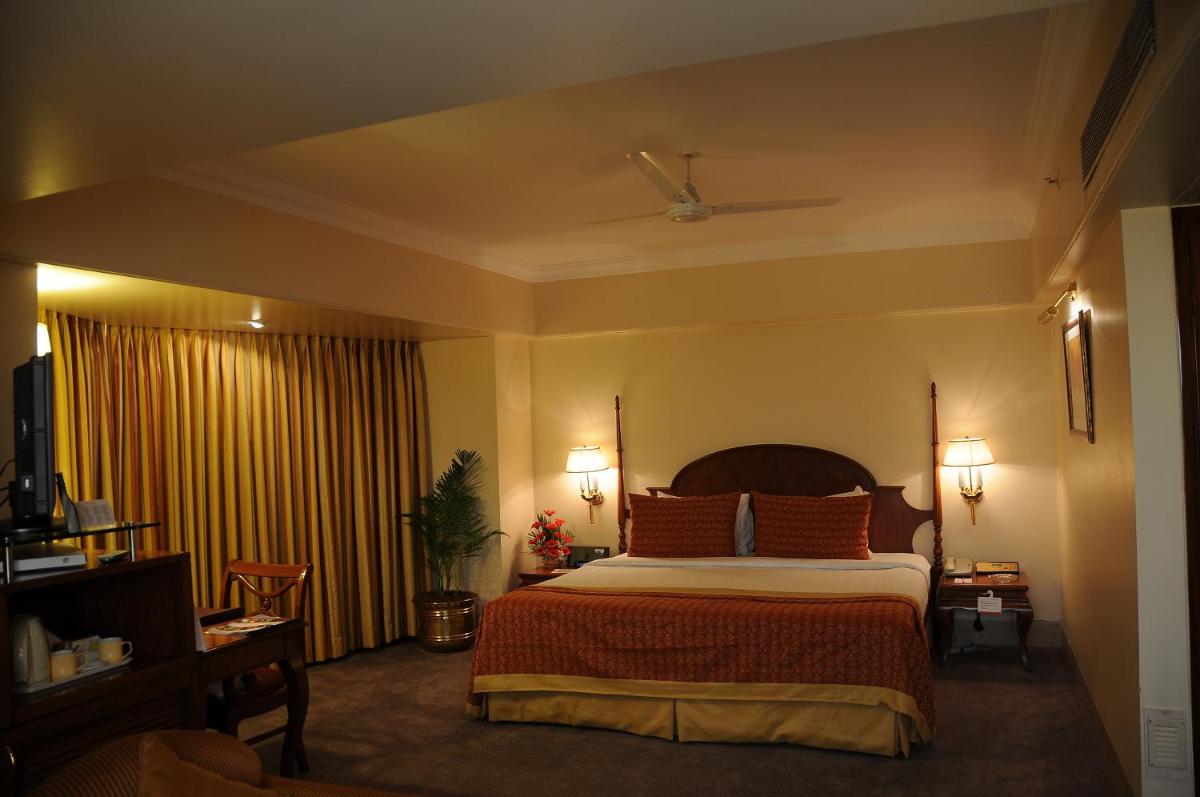 a hotel room with a bed and a television at Ramada Plaza By Wyndham Palm Grove in Mumbai