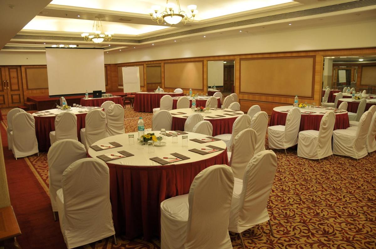 a conference room with tables and chairs and a screen at Ramada Plaza By Wyndham Palm Grove in Mumbai