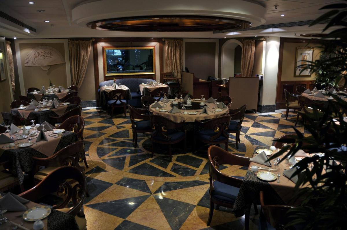 a restaurant with tables and chairs in a room at Ramada Plaza By Wyndham Palm Grove in Mumbai