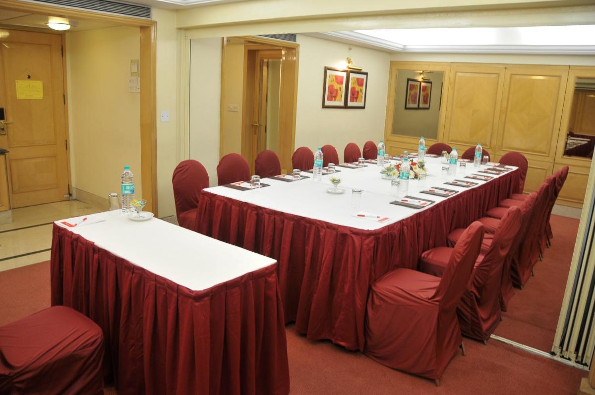 a conference room with a long table and red chairs at Ramada Plaza By Wyndham Palm Grove in Mumbai
