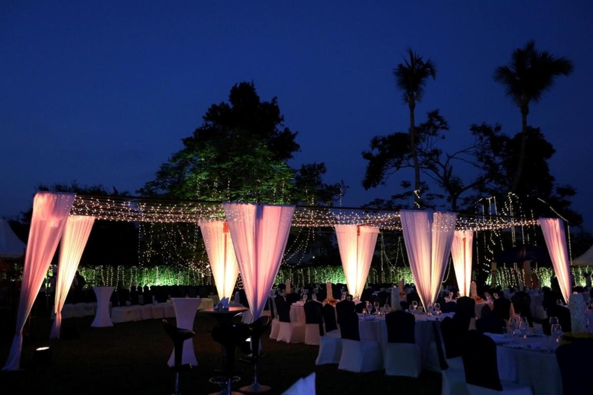 a group of tables with chairs and lights at night at Greenpark Chennai in Chennai