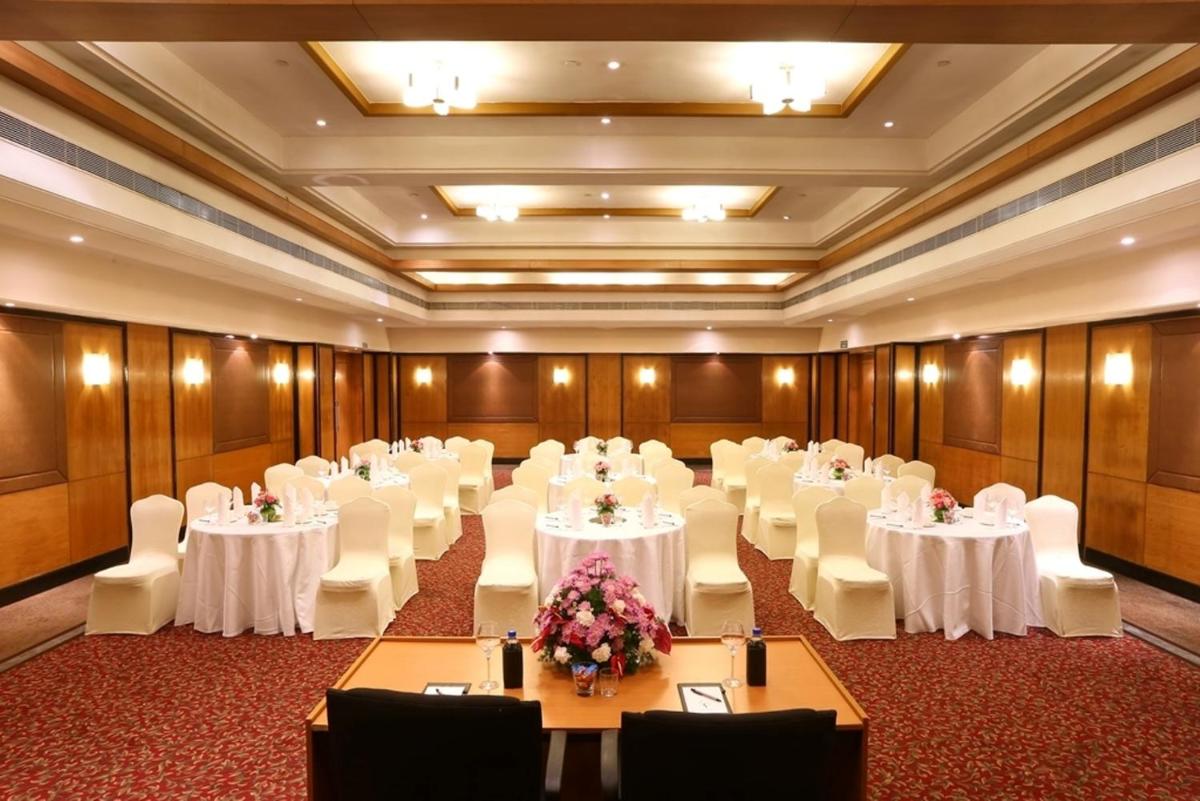 a room filled with tables and chairs with white tablecloths at Greenpark Chennai in Chennai