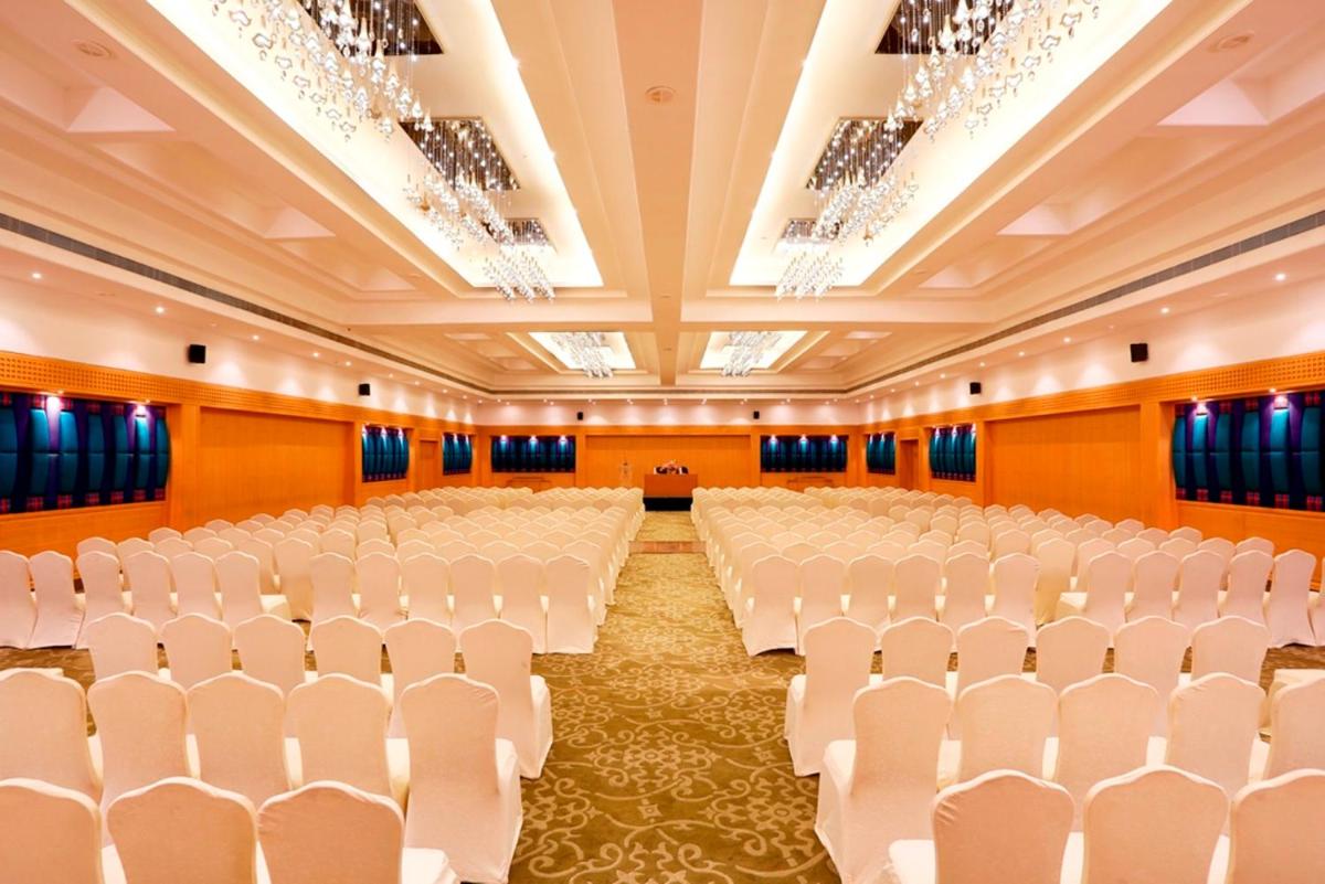 an empty banquet hall with white chairs and chandeliers at Greenpark Chennai in Chennai