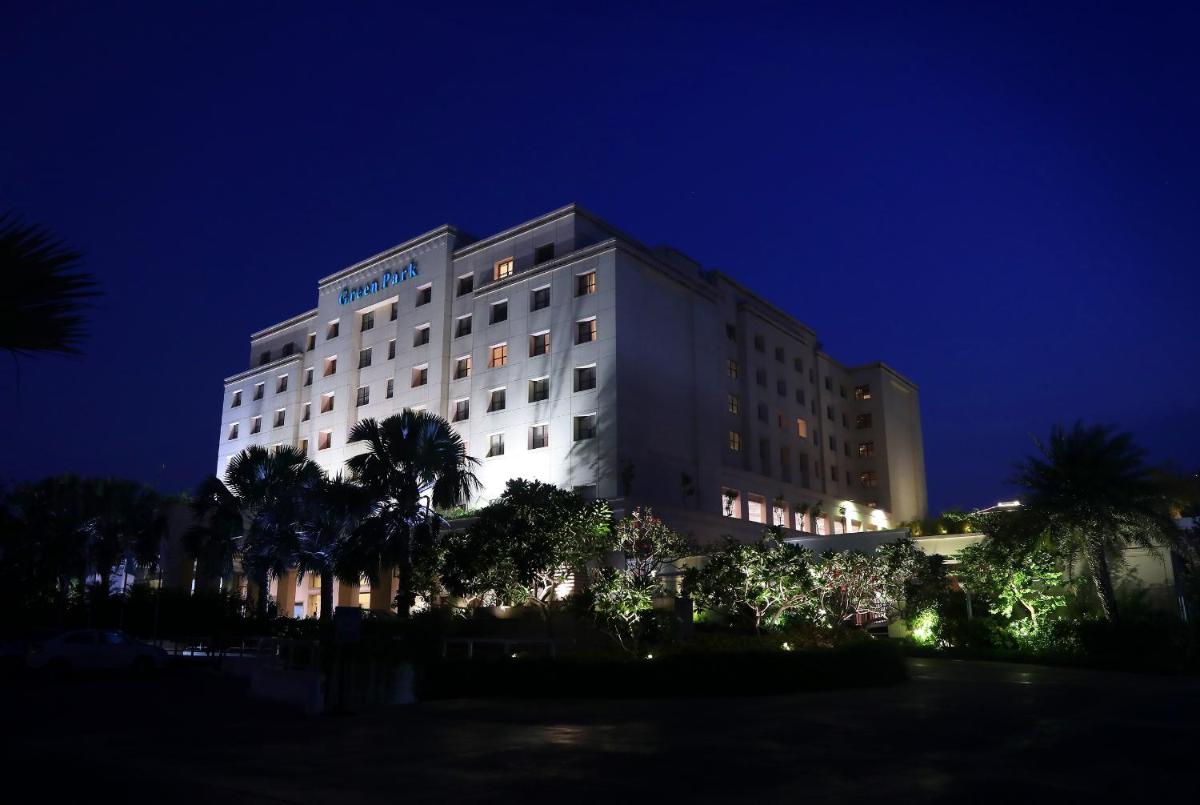 a hotel at night with palm trees in front of it at Greenpark Chennai in Chennai
