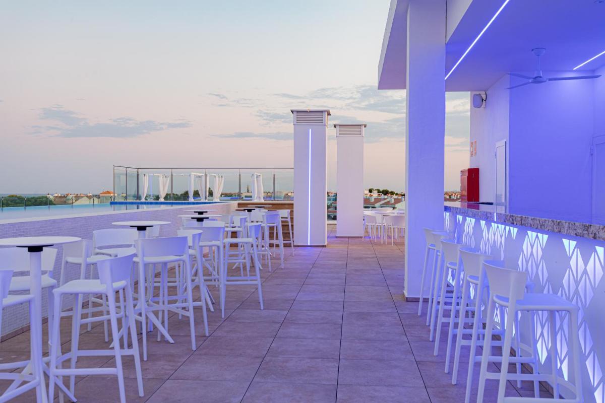 un bar con sillas blancas y mesas en un patio en Alcossebre Sea Experience, en Alcossebre