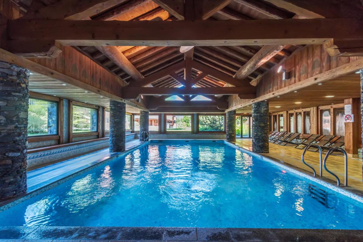 - une piscine dans une maison dotée d'un plafond en bois dans l'établissement Résidence Pierre & Vacances Premium Les Fermes Du Soleil, aux Carroz d'Arâches