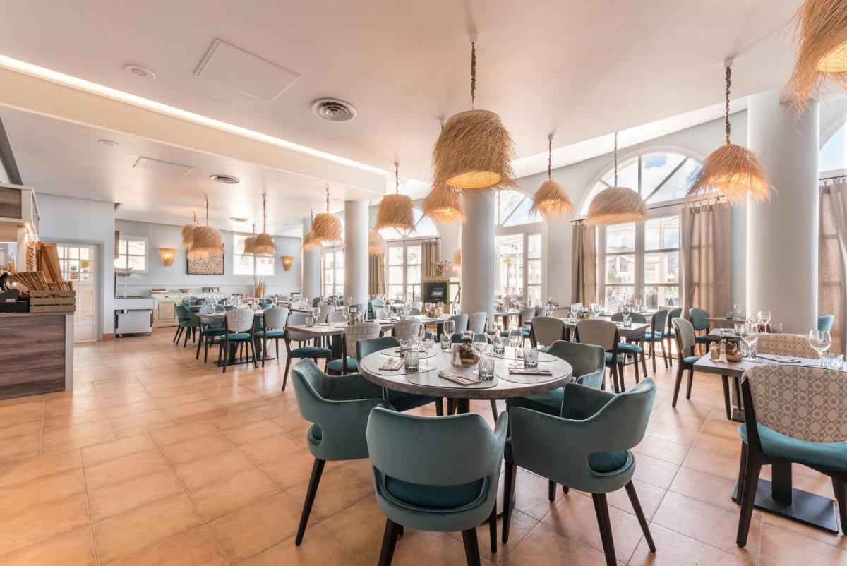 une salle à manger avec tables, chaises et fenêtres dans l'établissement Hôtel de l'Esterel Pierre & Vacances, à Agay