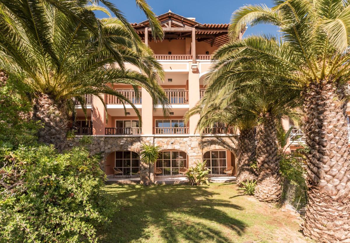 un grand bâtiment avec des palmiers devant dans l'établissement Hôtel de l'Esterel Pierre & Vacances, à Agay