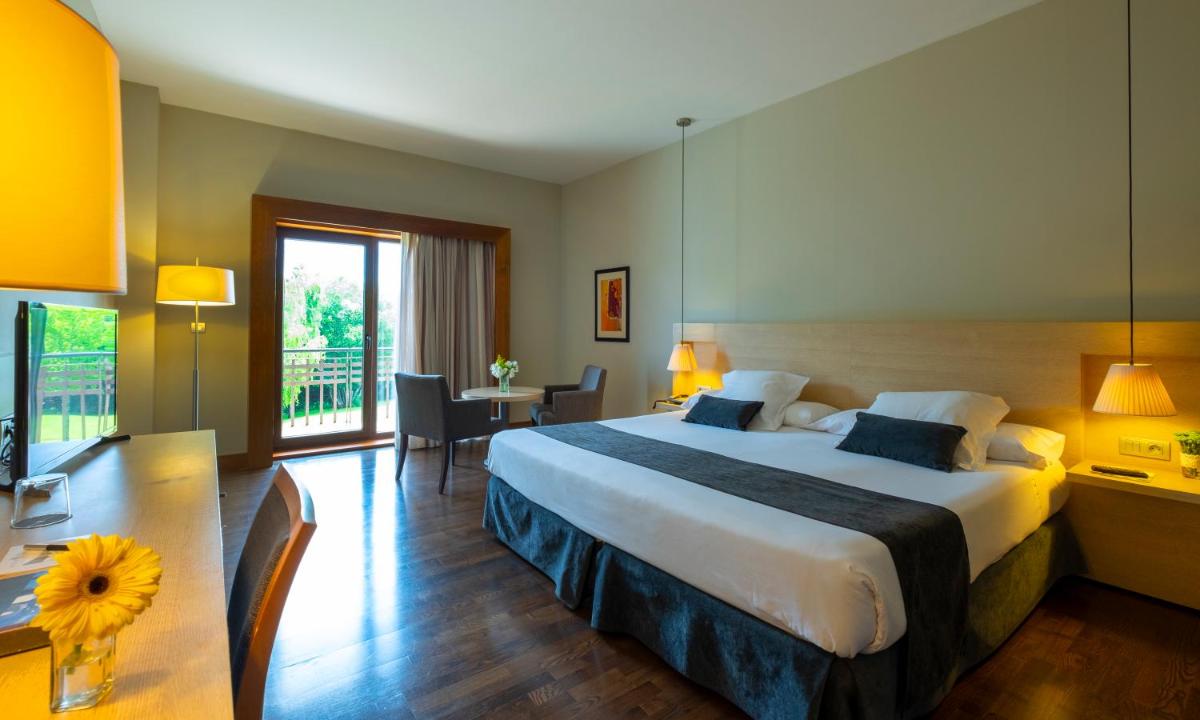 Una habitación de hotel con una cama grande y un escritorio. en Hotel Spa Attica21 Vilalba, en Vilalba