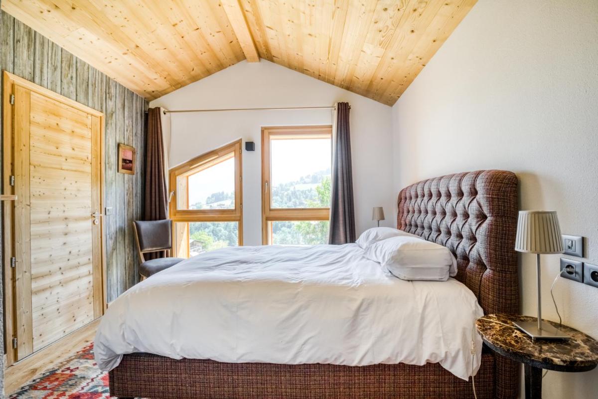 une chambre avec un grand lit et une fenêtre dans l'établissement TERRESENS - Les Fermes du Mont-Blanc, à Combloux
