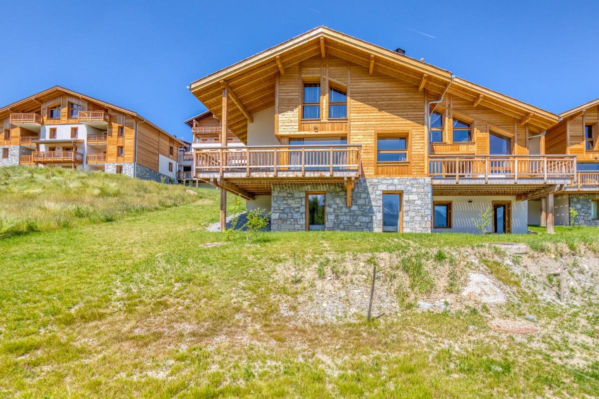 une maison en rondins avec une terrasse sur une colline dans l'établissement TERRESENS - Les Fermes du Mont-Blanc, à Combloux