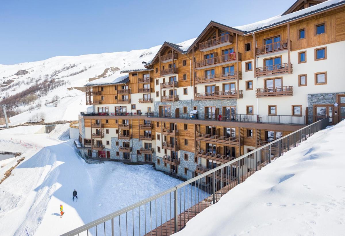un bâtiment sous la neige avec des skieurs sur la glace dans l'établissement Résidence Club MMV Le Cœur des Loges, aux Menuires
