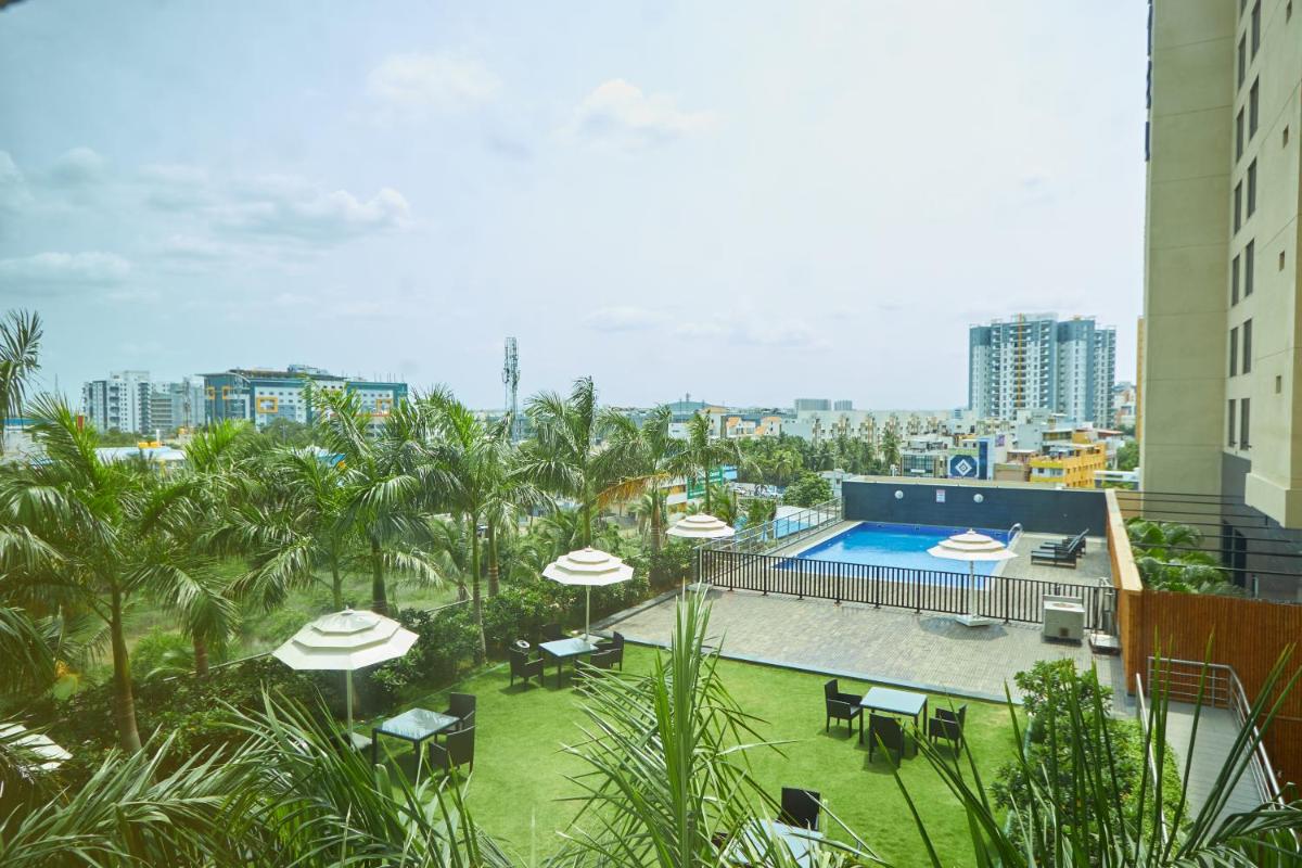 a swimming pool with umbrellas and chairs and a building at Novotel Chennai OMR in Chennai