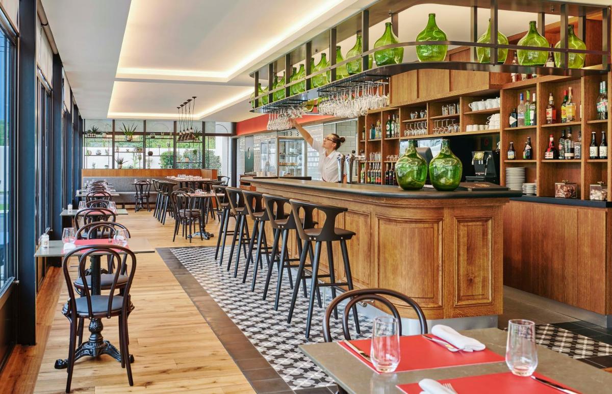 un restaurant avec un bar avec tables et chaises dans l'établissement Château Saint-Jean, Relais & Châteaux, à Montluçon
