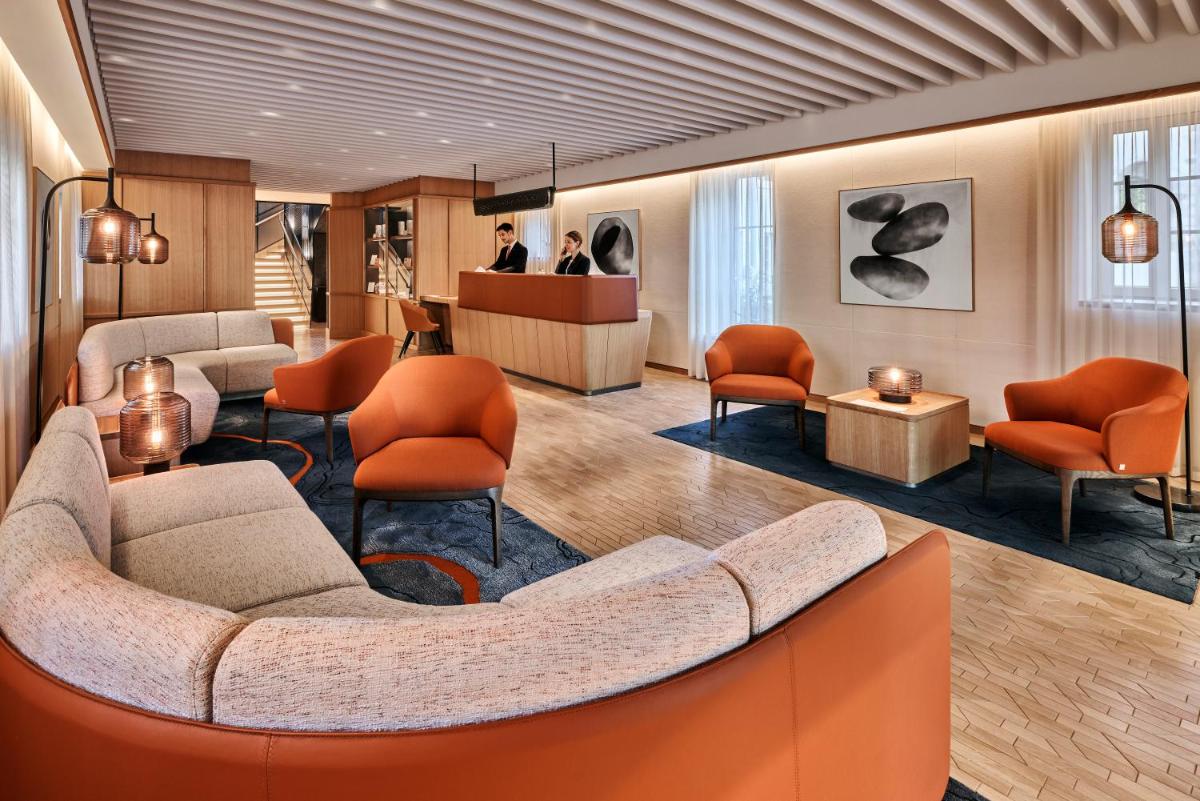 - un hall avec un canapé et des chaises orange dans l'établissement Château Saint-Jean, Relais & Châteaux, à Montluçon