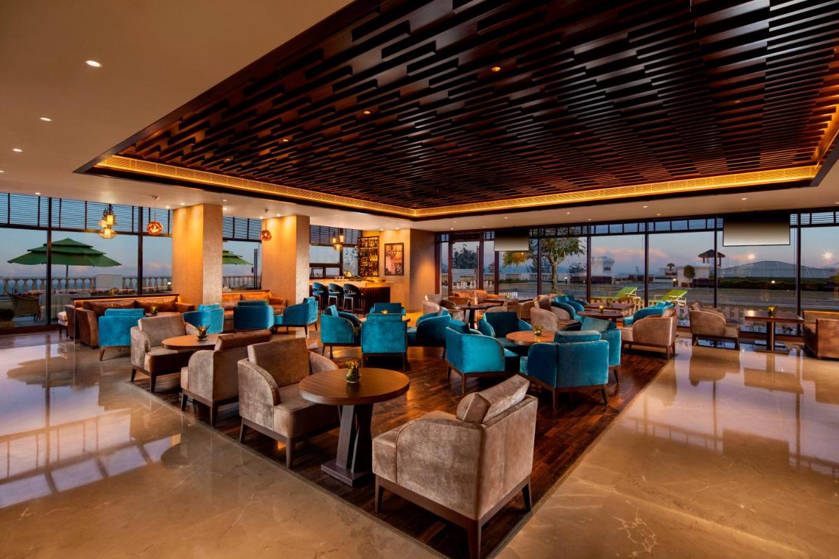 a restaurant with blue chairs and tables and windows at Jaypee Residency Manor in Mussoorie