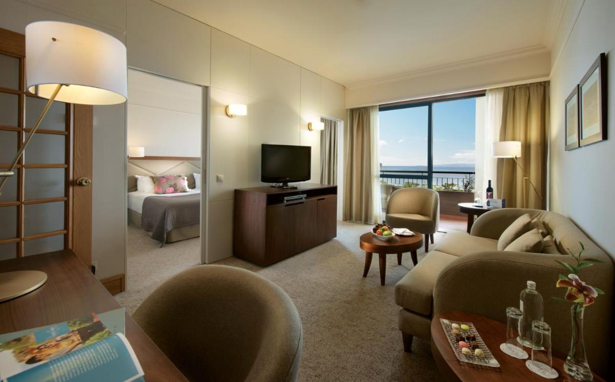 um quarto de hotel com um sofá e uma televisão em The Cliff Bay - PortoBay no Funchal