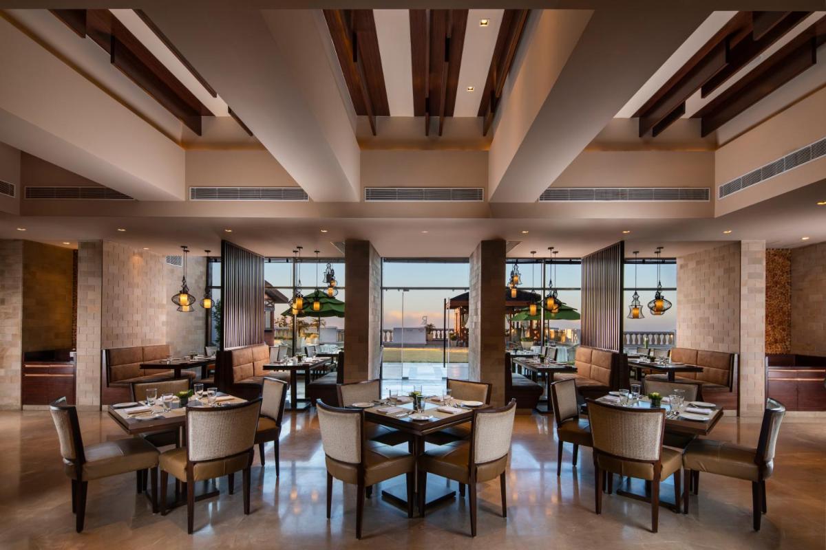 a dining room with tables and chairs and windows at Jaypee Residency Manor in Mussoorie