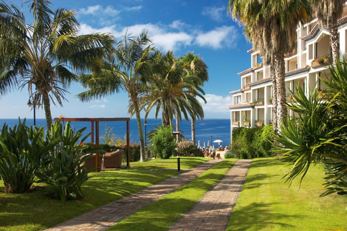 um resort com palmeiras e o oceano ao fundo em The Cliff Bay - PortoBay no Funchal