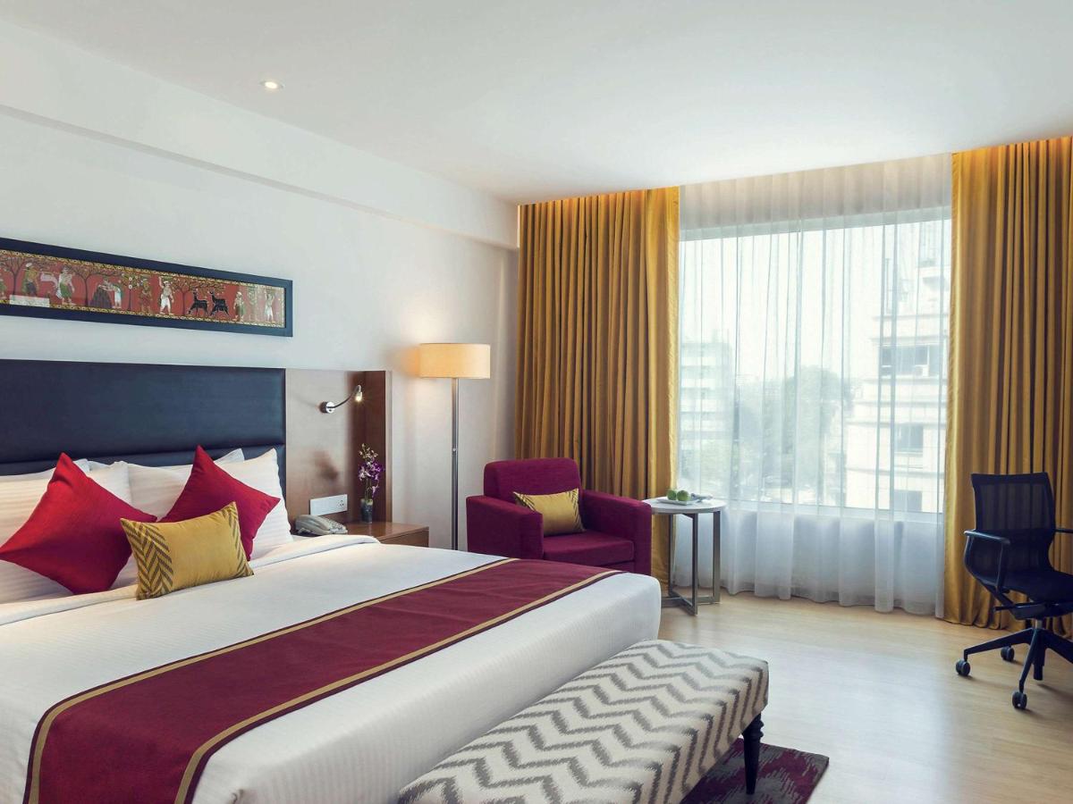 a hotel room with a bed and a large window at Mercure Hyderabad KCP Banjara Hills, An Accor Hotel in Hyderabad