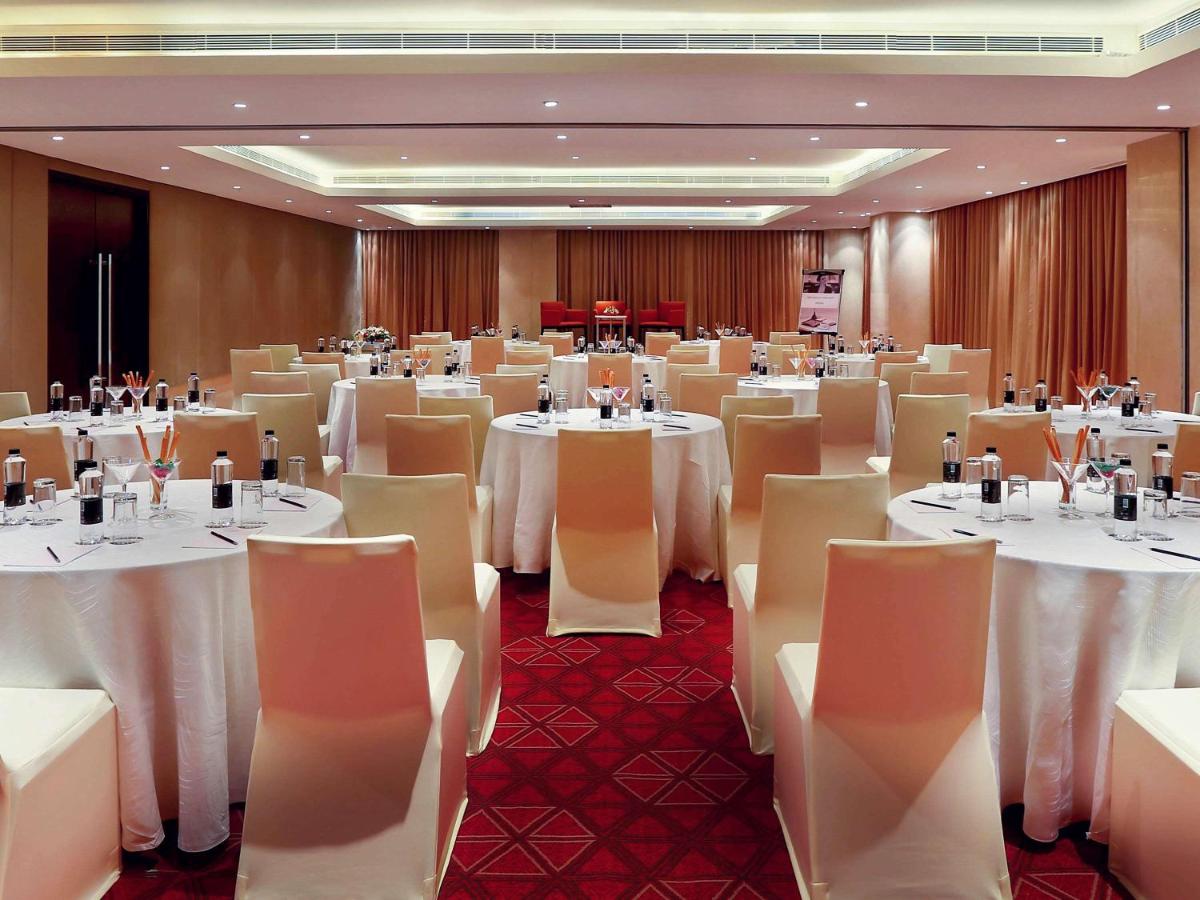 a banquet hall with white tables and chairs at Mercure Hyderabad KCP Banjara Hills, An Accor Hotel in Hyderabad