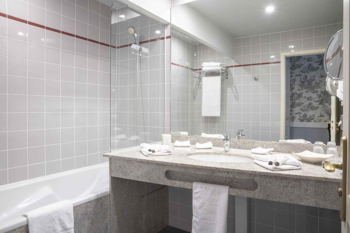 une salle de bain avec un lavabo et une baignoire dans l'établissement Le Manoir De La Poterie & Spa, à Cricquebœuf