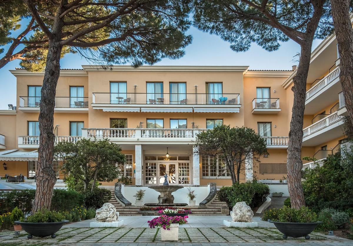 una vista exterior de un gran edificio con árboles en S'Agaró Hotel Spa & Wellness, en S'Agaró