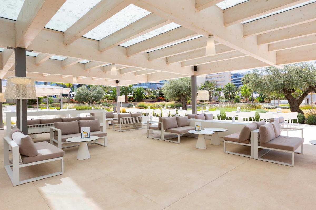 Un patio con sofás y mesas y un gran techo. en Hipotels Gran Playa de Palma, en Playa de Palma