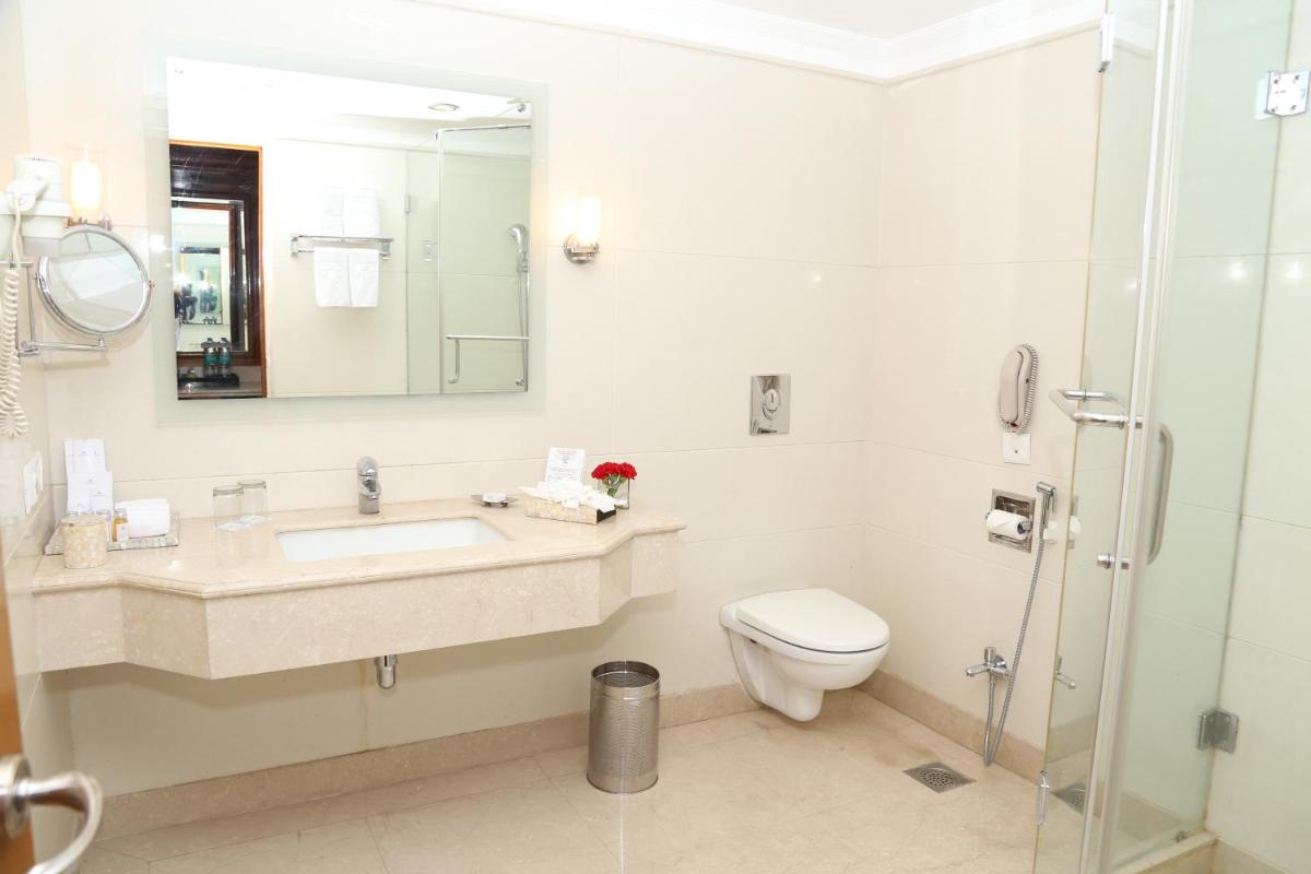 a bathroom with a sink and a toilet and a mirror at Jaypee Residency Manor in Mussoorie a bathroom with a sink and a toilet and a mirror at Jaypee Residency Manor in Mussoorie