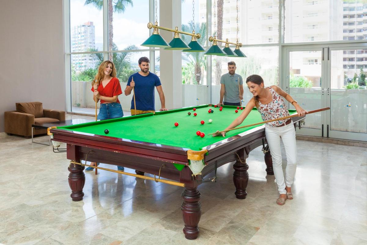 Un grupo de personas de pie alrededor de una mesa de billar. en Hotel & SPA Dynastic, en Benidorm