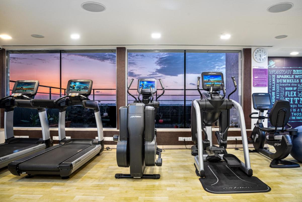 a gym with cardio machines in front of a window at Mercure Hyderabad KCP Banjara Hills, An Accor Hotel in Hyderabad