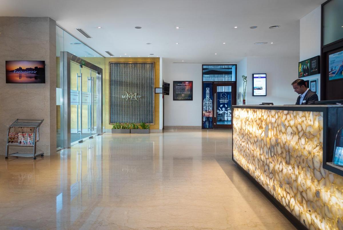 a man standing at a counter in a lobby at Mercure Hyderabad KCP Banjara Hills, An Accor Hotel in Hyderabad