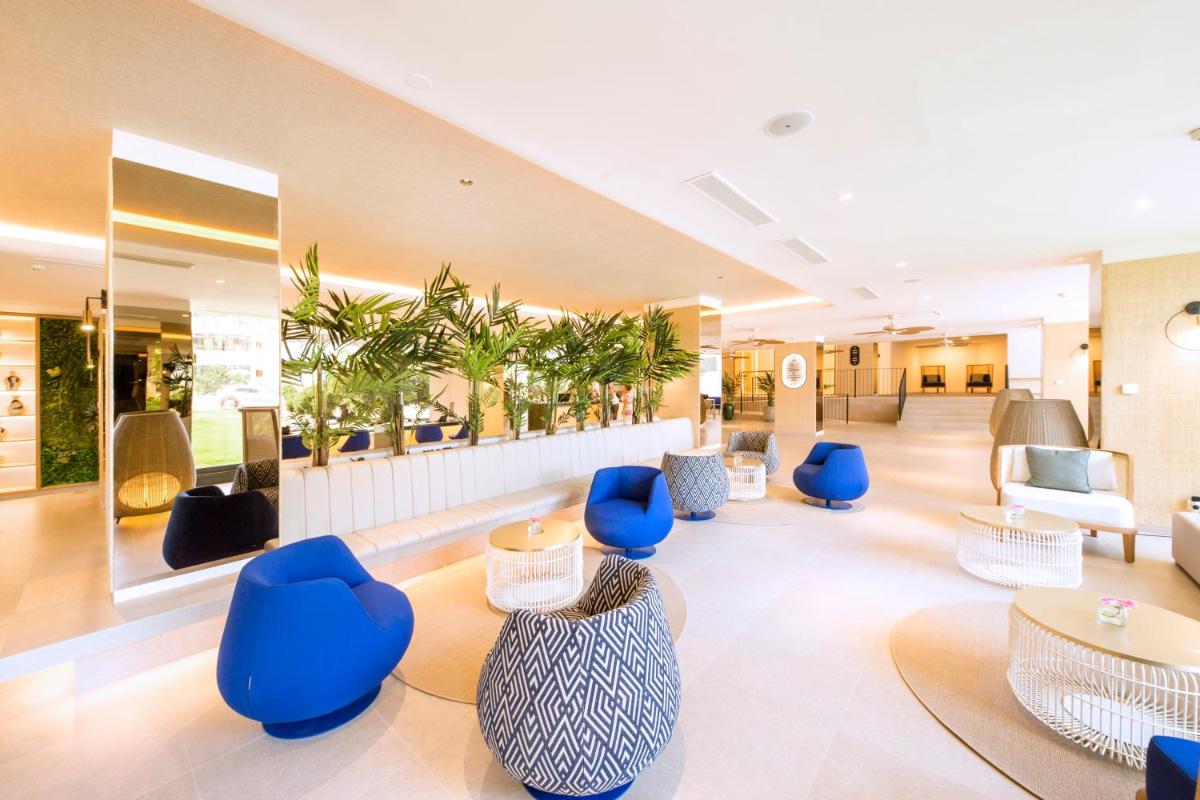 un vestíbulo con sillas azules, mesas y plantas en FERGUS Style Tobago - Adults Only, en Palmanova