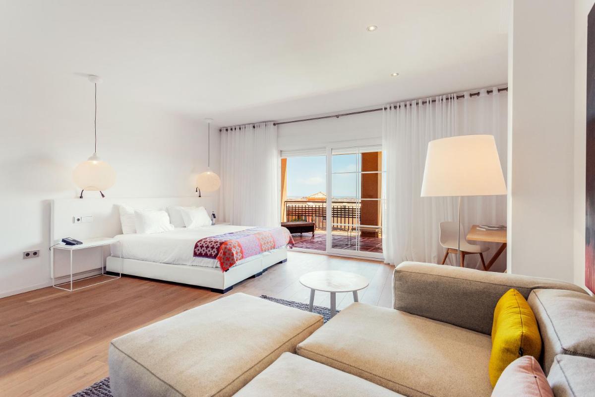 Un dormitorio blanco con una cama y un sofá. en Ama Islantilla Resort, en Islantilla