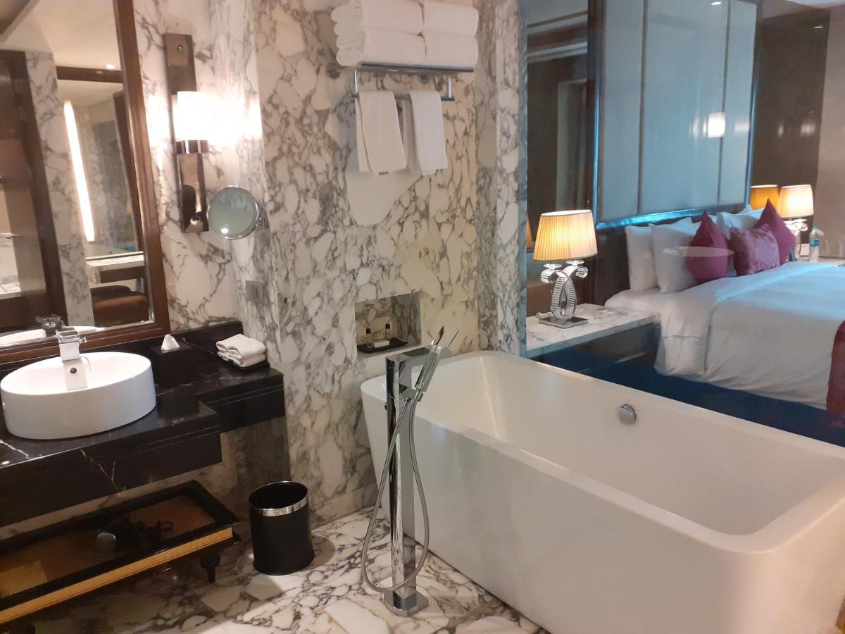 a bathroom with a tub and a sink and a bed at Radisson Blu Jaipur in Jaipur
