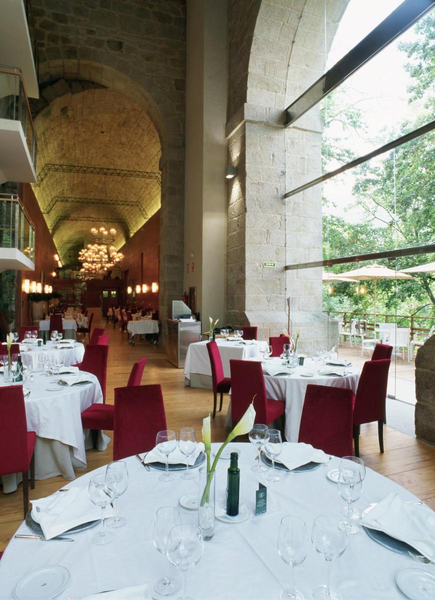 Un comedor con mesas blancas y sillas rojas. en Parador de Santo Estevo, en Santo Estevo de Rivas de Sil