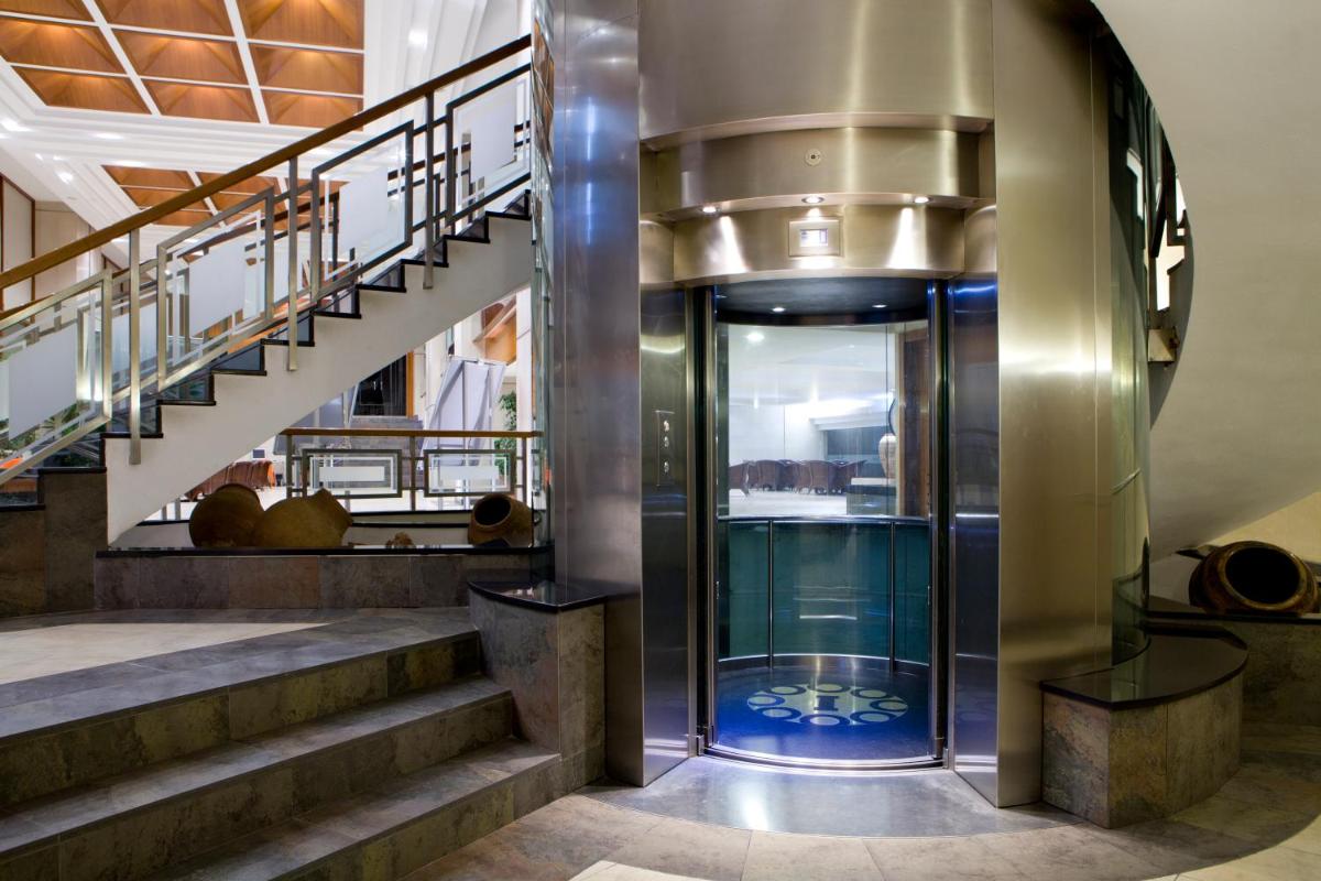 un vestíbulo con escaleras y un ascensor de cristal en Intelier Orange, en Benicàssim