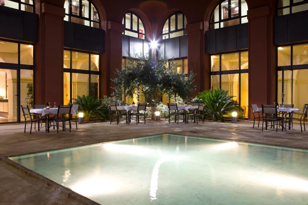 Una piscina vacía en un edificio con mesas y sillas. en Intelier Airén, en Alcázar de San Juan