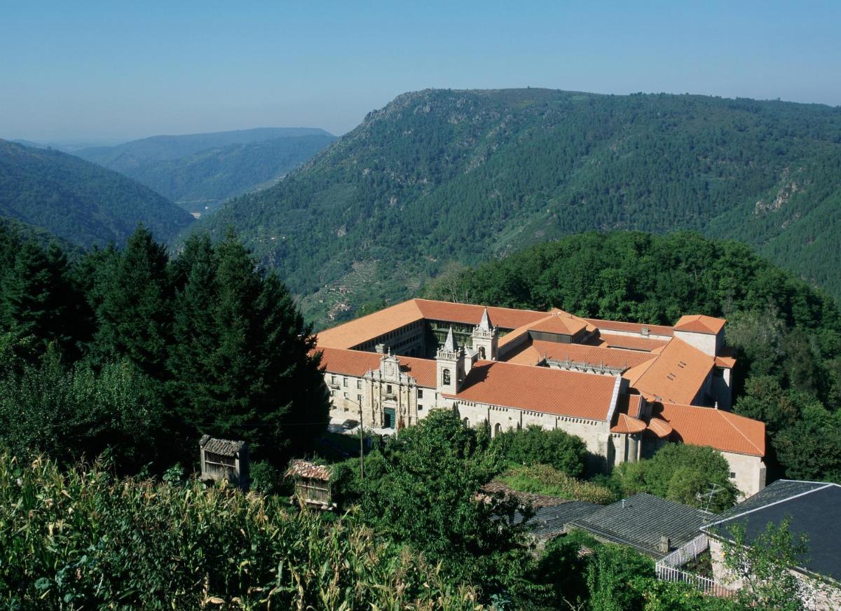 un edificio en una colina con montañas al fondo en Parador de Santo Estevo, en Santo Estevo de Rivas de Sil