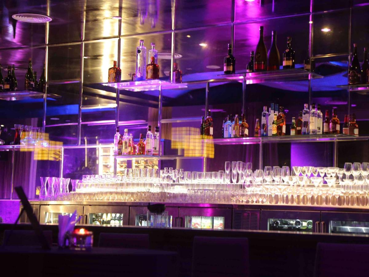a bar filled with lots of glasses and purple lights at Mercure Hyderabad KCP Banjara Hills, An Accor Hotel in Hyderabad