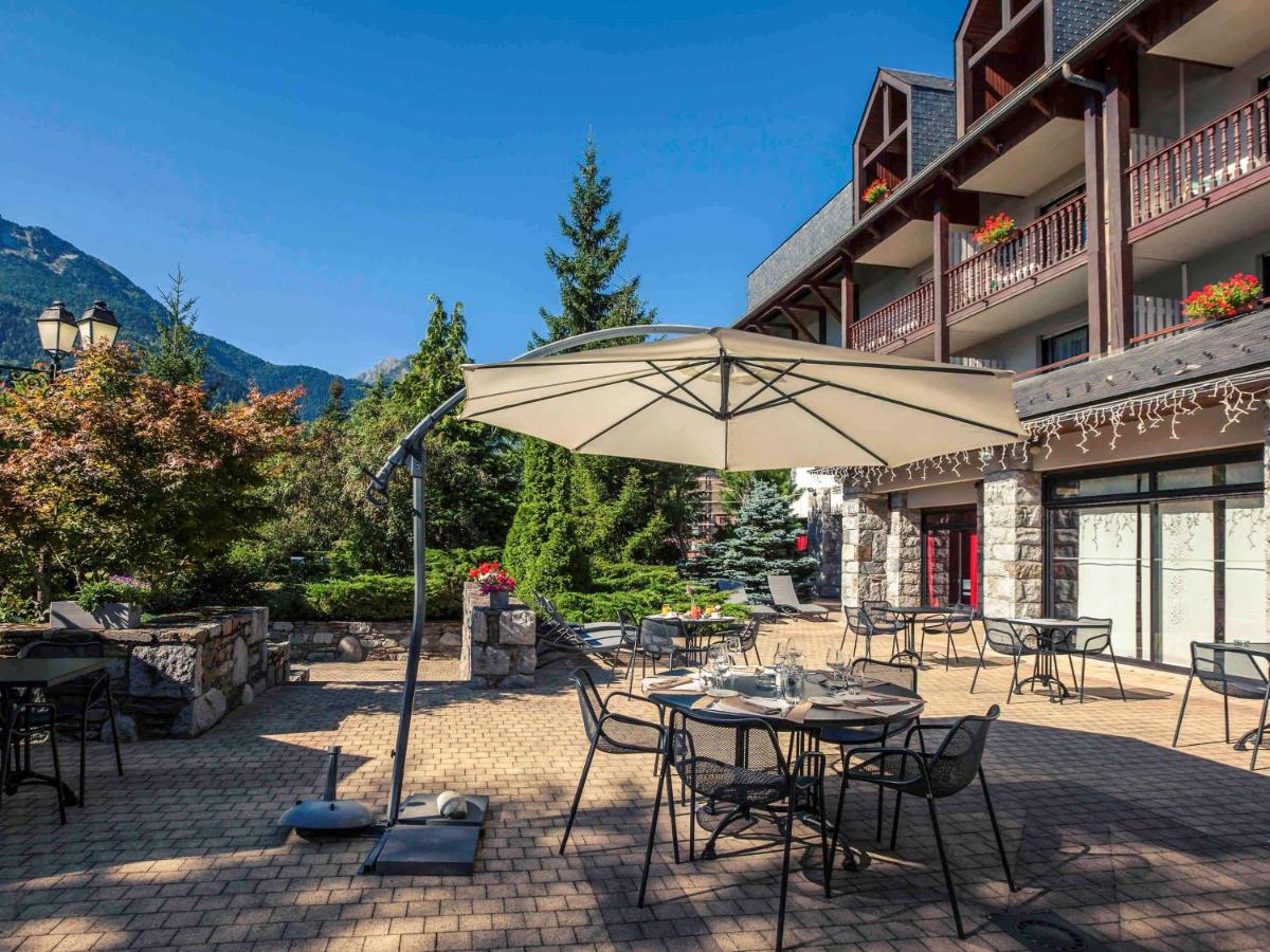une terrasse avec tables, chaises et parasol dans l'établissement Mercure Saint-Lary, à Saint-Lary-Soulan