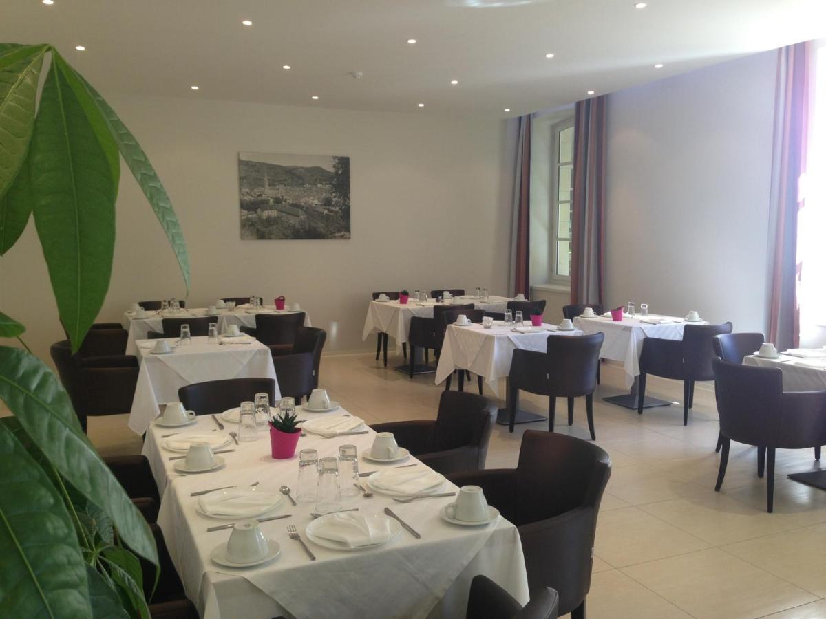 une salle à manger avec des tables blanches et des chaises noires dans l'établissement Le 1837, à Saint-Affrique