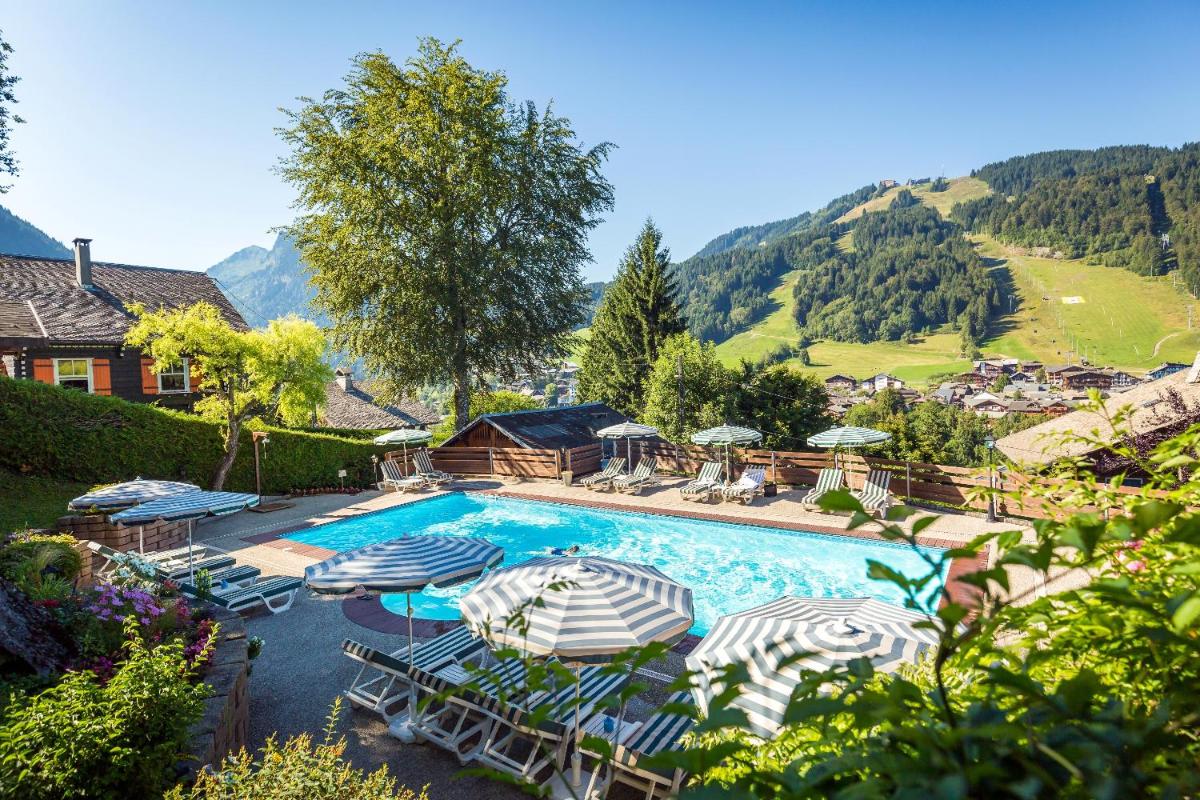 une grande piscine avec parasols et chaises dans l'établissement Hotel & Spa Le Dahu, à Morzine