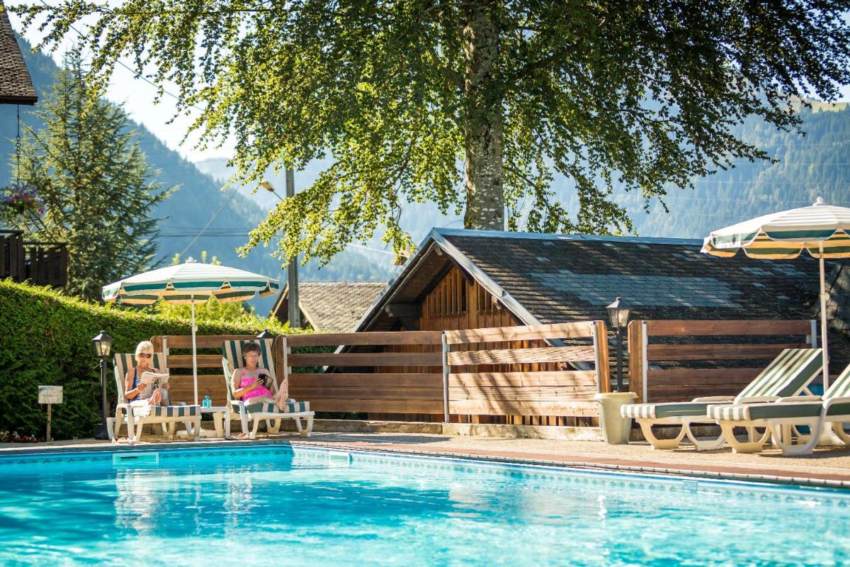 2 femmes assises sur des chaises à côté d'une piscine dans l'établissement Hotel & Spa Le Dahu, à Morzine