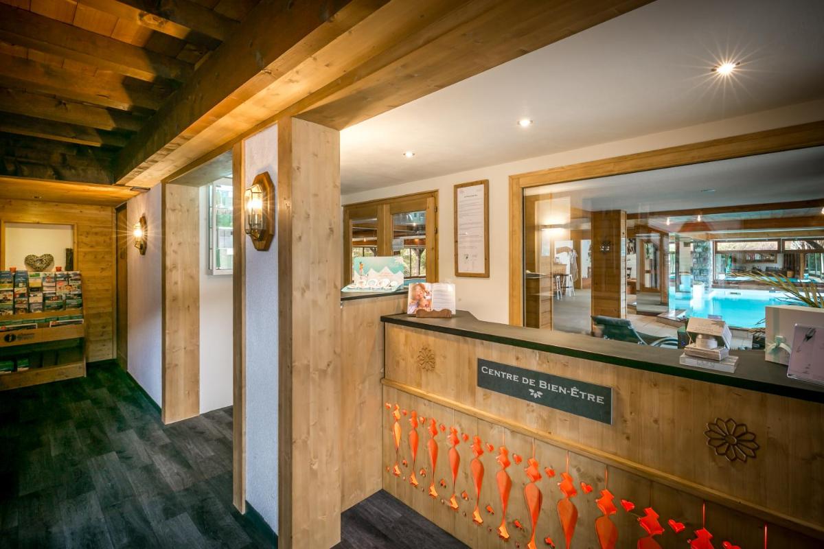 un bar dans un restaurant avec une piscine en arrière-plan dans l'établissement Hotel & Spa Le Dahu, à Morzine
